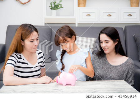 Asian mother and aunt see daughter putting coin Asian mother and aunt see daughter putting coin 43456914