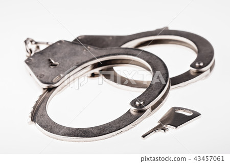 Pair of handcuffs and key on white background. Pair of handcuffs and key on white background. 43457061