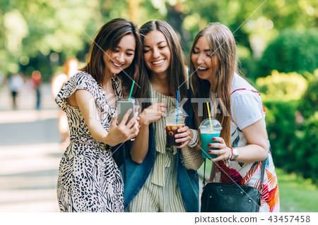 Summer lifestyle portrait multiracial women enjoy nice day, holding glasses of milkshakes. Happy Summer lifestyle portrait multiracial women enjoy nice day, holding glasses of milkshakes. Happy 43457458