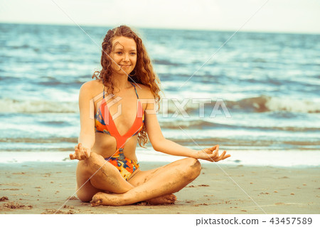 Young woman practices yoga on the beach in summer. 43457589