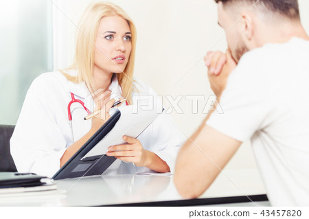 Woman Doctor and Male Patient in Hospital Office 43457820