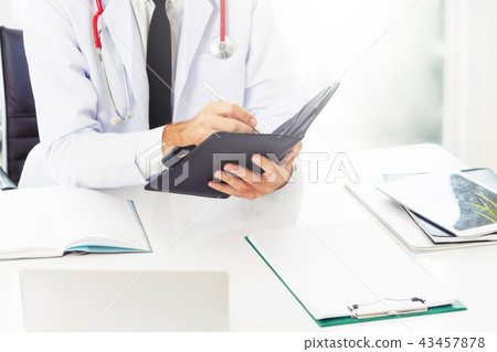 Doctor reading while writing note on a book. 43457878