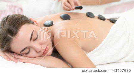 Hot stone massage treatment by therapist in spa. 43457980