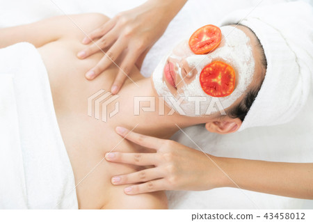 Woman get facial mask with tomato cream extract. Woman get facial mask with tomato cream extract. 43458012