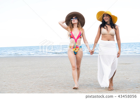Happy women go sunbathing at sand beach in summer. 43458056