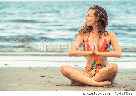 Young woman practices yoga on the beach in summer. 43458058