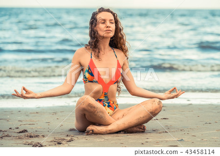 Young woman practices yoga on the beach in summer. 43458114