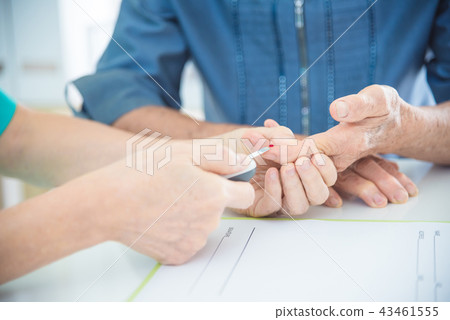 Nurse Using Glucometer On Senior Patient's finger 43461555