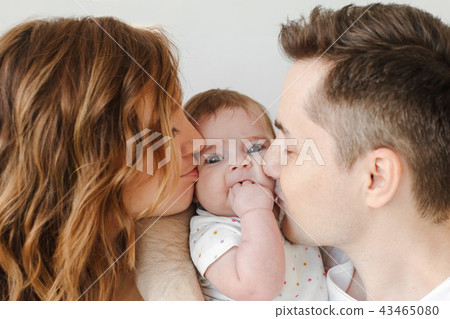Parents kissing baby in cheeks 43465080