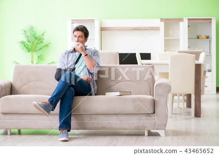 Young student man with hand injury sitting on the sofa Young student man with hand injury sitting on the sofa 43465652