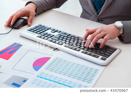 Finance professional working on keyboard with reports Finance professional working on keyboard with reports 43470967