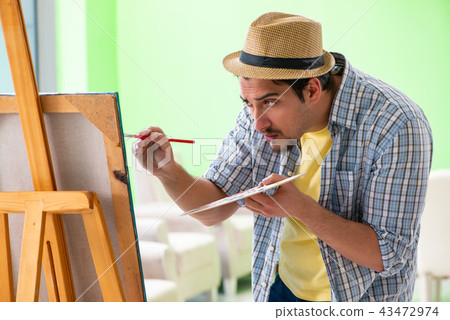 Young male artist working on new painting in his studio Young male artist working on new painting in his studio 43472974