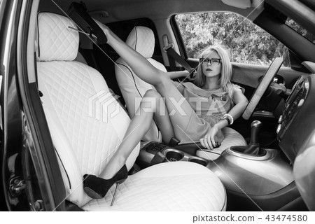 Slender sexy girl on high heels lies in the car. Slender sexy girl on high heels lies in the car. 43474580