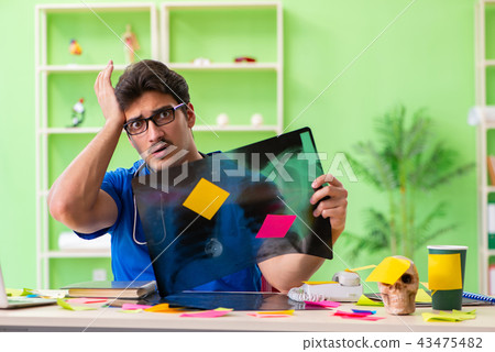 Young doctor sitting in hospital with many conflicting prioritie 43475482