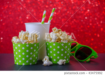 two cups of popcorn, drink and glasses for movie on red bokeh background, selective focus two cups of popcorn, drink and glasses for movie on red bokeh background, selective focus 43475992