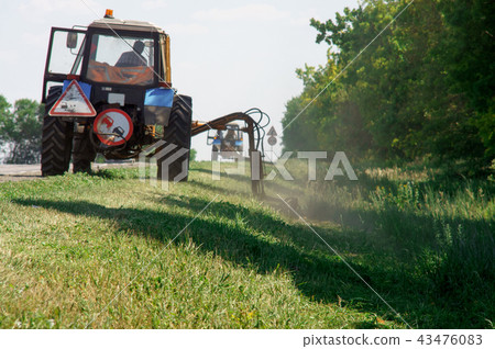 Tractors machines mowing lawn grass along road 43476083