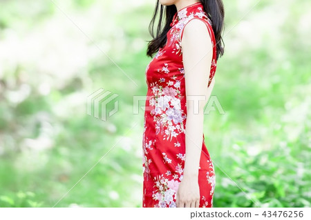 A woman in a Chinese dress standing in the forest A woman in a Chinese dress standing in the forest 43476256