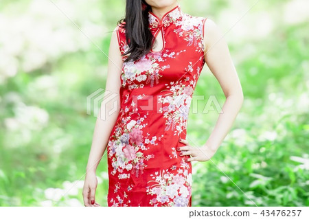 A woman in a Chinese dress standing in the forest A woman in a Chinese dress standing in the forest 43476257