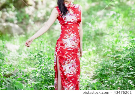 A woman in a Chinese dress standing in the forest A woman in a Chinese dress standing in the forest 43476261