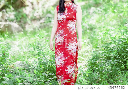 A woman in a Chinese dress standing in the forest 43476262
