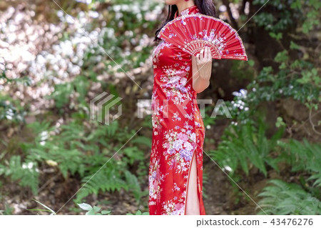 A woman in a Chinese dress standing in the forest A woman in a Chinese dress standing in the forest 43476276