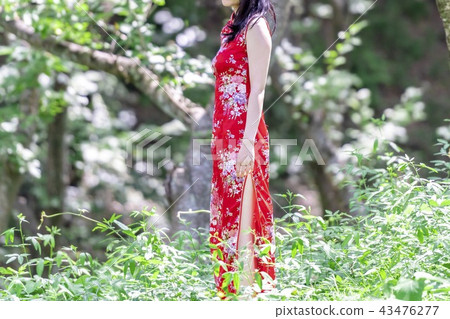A woman in a Chinese dress standing in the forest A woman in a Chinese dress standing in the forest 43476277