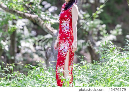A woman in a Chinese dress standing in the forest A woman in a Chinese dress standing in the forest 43476279
