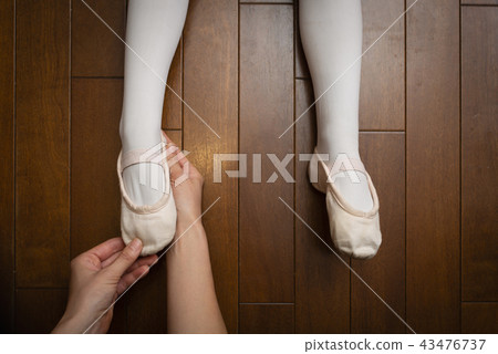 Mother's hand putting her toe shoes on 43476737