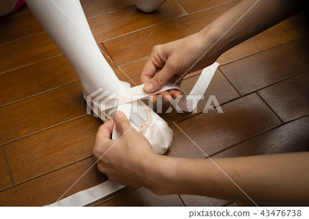Mother's hand putting her toe shoes on 43476738