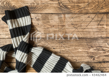 Striped wool scarf on brown wood background. Striped wool scarf on brown wood background. 43482464