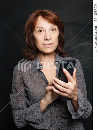 Mature business woman holding smartphone 43484709