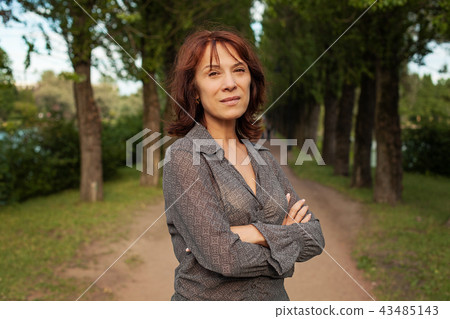 Mature woman walking in summer park outdoors Mature woman walking in summer park outdoors 43485143