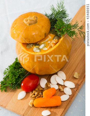 Tasty homemade pumpkin soup puree served in pumpkin at wooden desk Tasty homemade pumpkin soup puree served in pumpkin at wooden desk 43486931