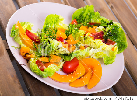 Salad of baked pumpkin, cherry tomatoes, sesame, sauce and greens 43487112