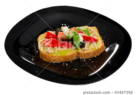 Sandwich with guacamole, canned tuna, feta, vegetables on black plate 43487398