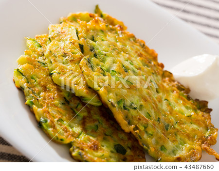 Image of zucchini fritters and white sauce at plate 43487660