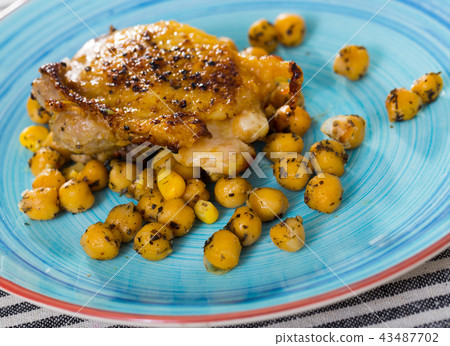 Dish of tasty fried chicken thighs served with cheakpea at plate 43487702