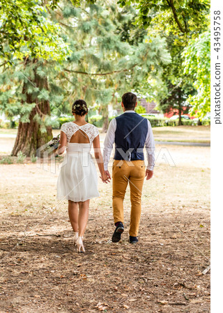 Bride and groom holding hand and walk in the garden 43495758