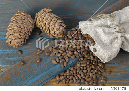 Cedar cones and nuts, poured from a bag on wooden Cedar cones and nuts, poured from a bag on wooden 43501476