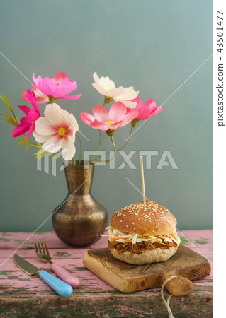 Pulled pork burger with paper flowers on wooden board Pulled pork burger with paper flowers on wooden board 43501477