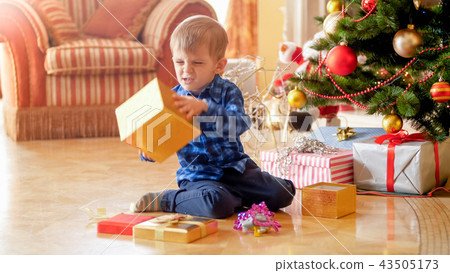 Portrait of little toddler boy is angry because of unwanted Christmas gift 43505173