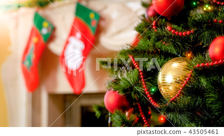 Closeup image of golden bauble and colorful lights on Christmas tree against mantelpiece 43505461