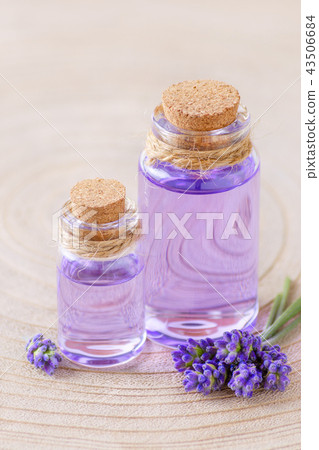 lavender oil in glass bottles and fresh lavender flowers on stump and wooden background 43506684