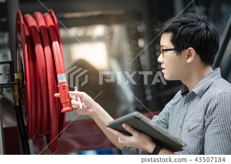 Asian technician checking fire hose reel Asian technician checking fire hose reel 43507184
