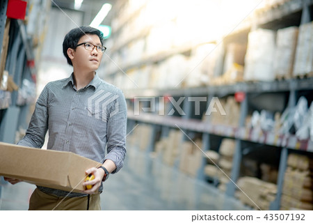 Asian man carrying cardboard box in warehouse Asian man carrying cardboard box in warehouse 43507192