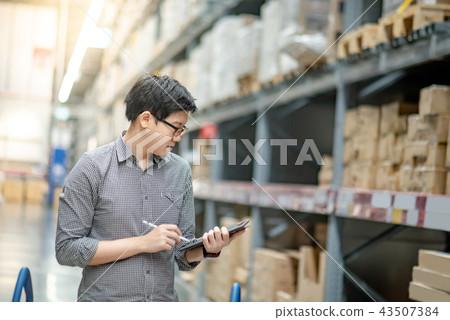 Asian man doing stocktaking on tablet in warehouse Asian man doing stocktaking on tablet in warehouse 43507384