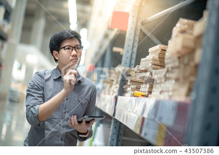 Asian man doing stocktaking on tablet in warehouse 43507386