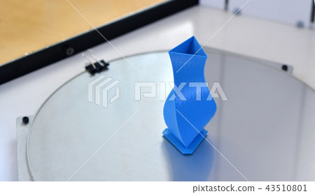 Bright blue object printed by 3d printer on 3d printer inside. 43510801