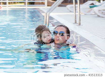 Happy mother and her daughter playing in swimming pool Happy mother and her daughter playing in swimming pool 43513313