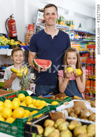Man with preteen kids choosing for fresh delicious fruits 43527389
